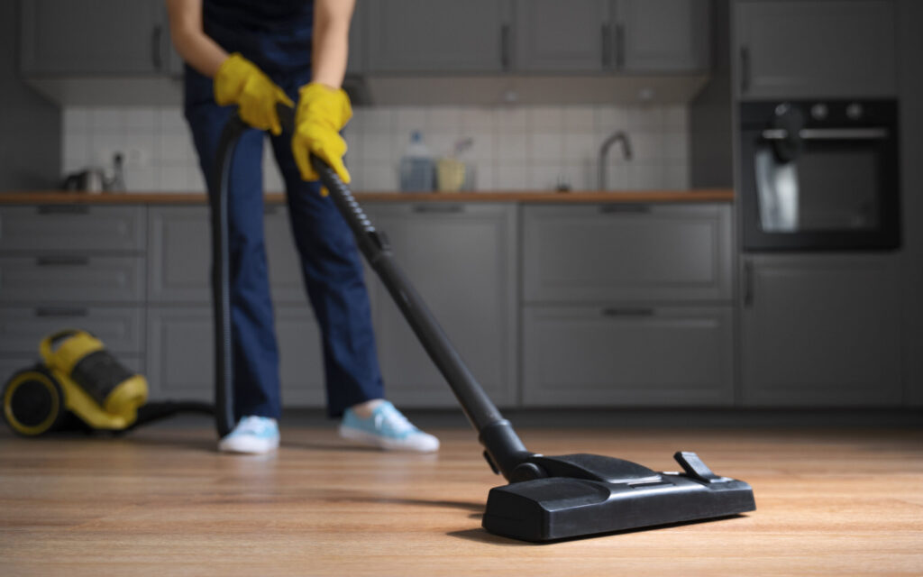 professional cleaner vacuuming hardwood and carpet floors in a residential home